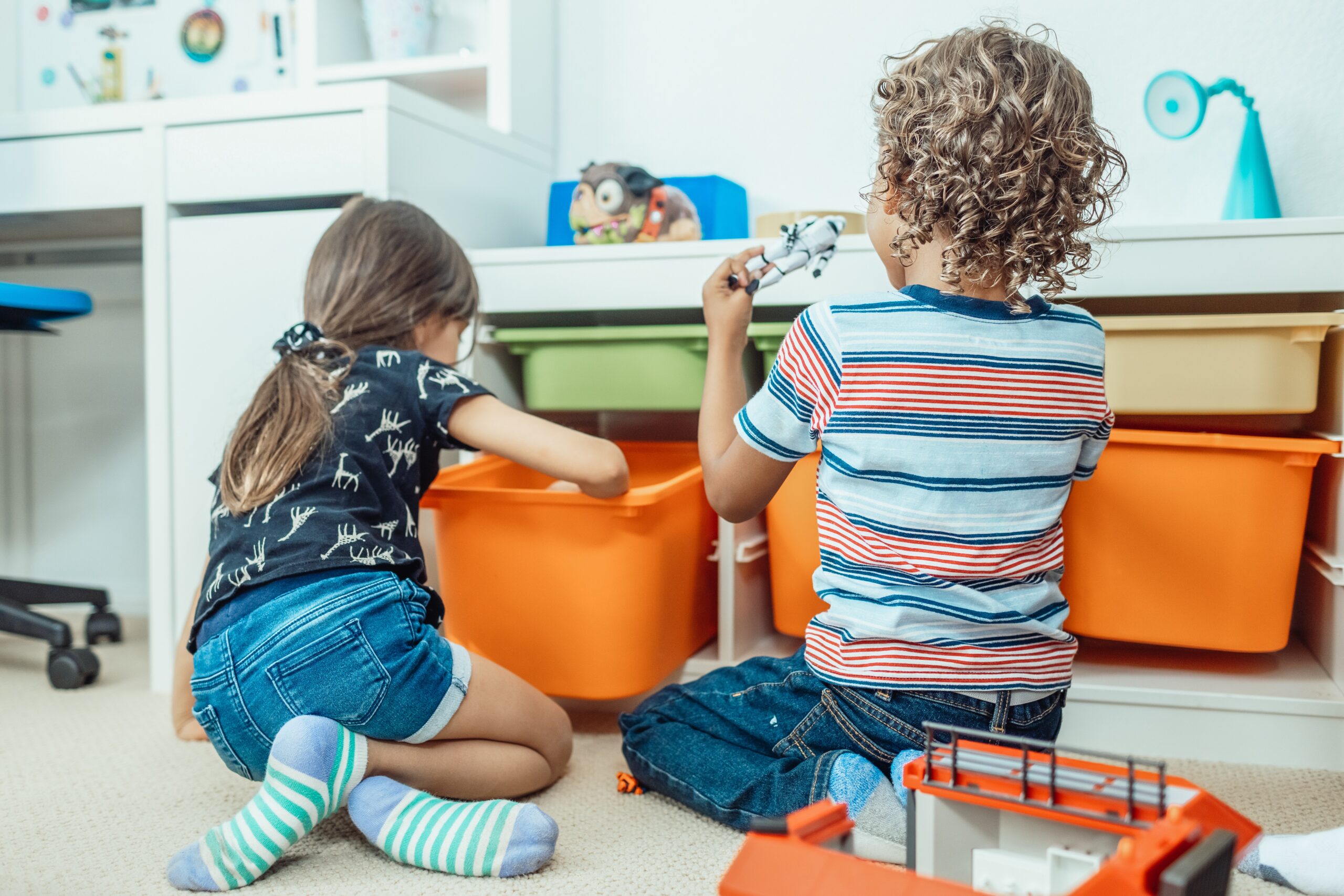 Children placing toys in storage