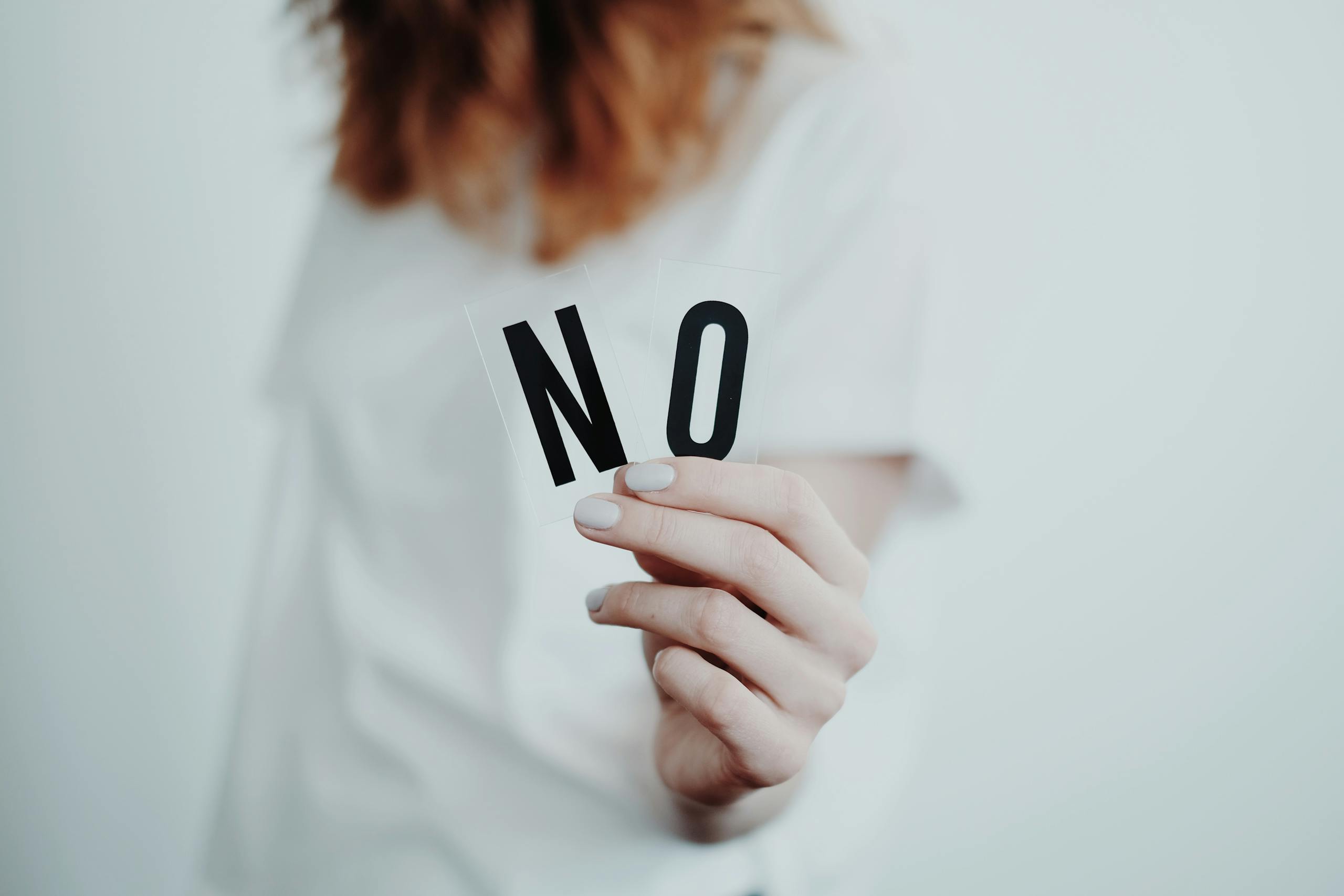 Close-up of a person holding a "No" sign, symbolizing rejection or disagreement.